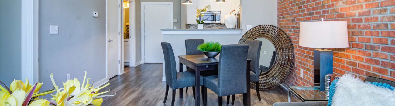 A dining room with a brick wall and a table with chairs.